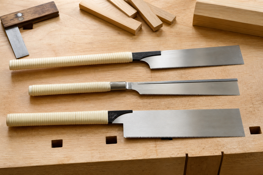 Comparación visual de sierras japonesas ryoba, dozuki y kataba sobre un banco de carpintería