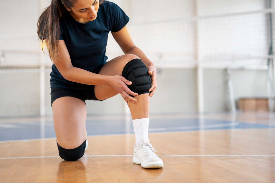 Jugadora de voleibol ajustando sus rodilleras antes de entrenar en cancha indoor