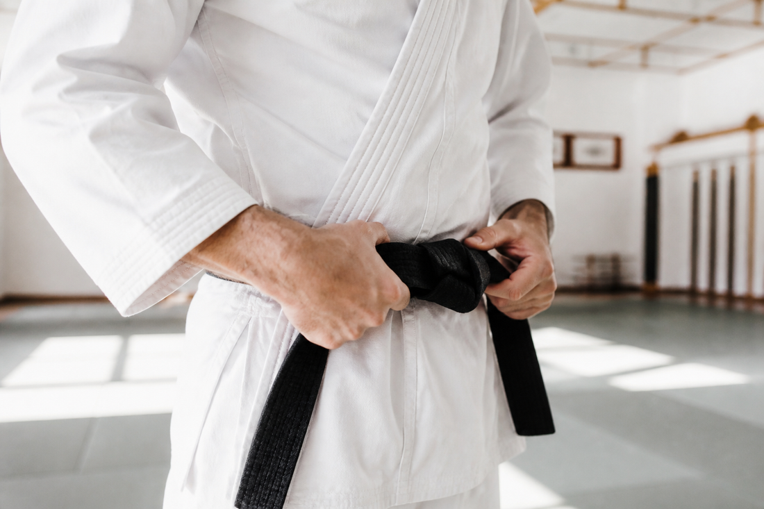 Practicante amarrando un cinturón de artes marciales antes de entrenar