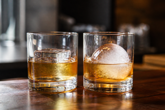 Comparación de un cubo grande y una bola de hielo en vasos de whisky